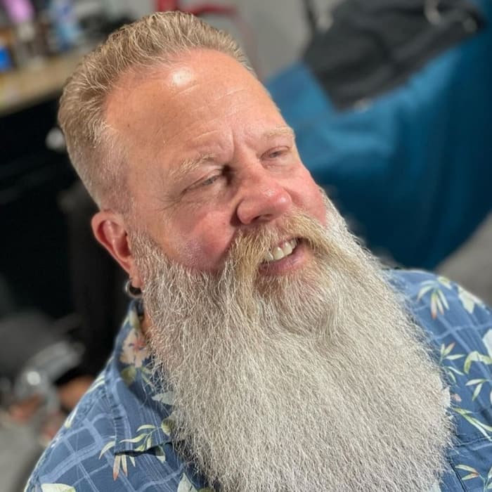 Smiling client with a long, freshly shaped grey beard