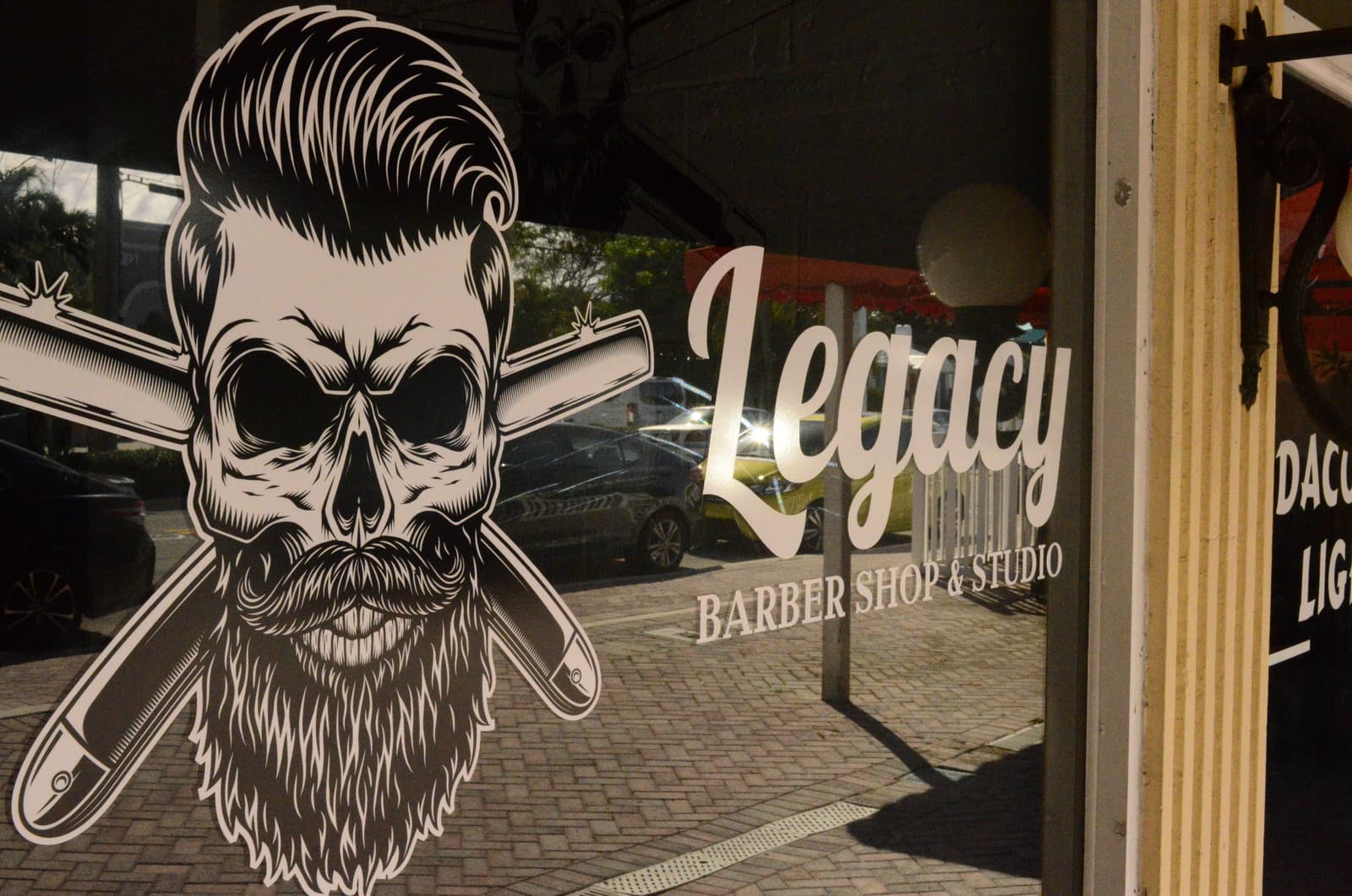 Legacy storefront window on NE 4th Ave with the skull-and-razors logo and script Legacy lettering